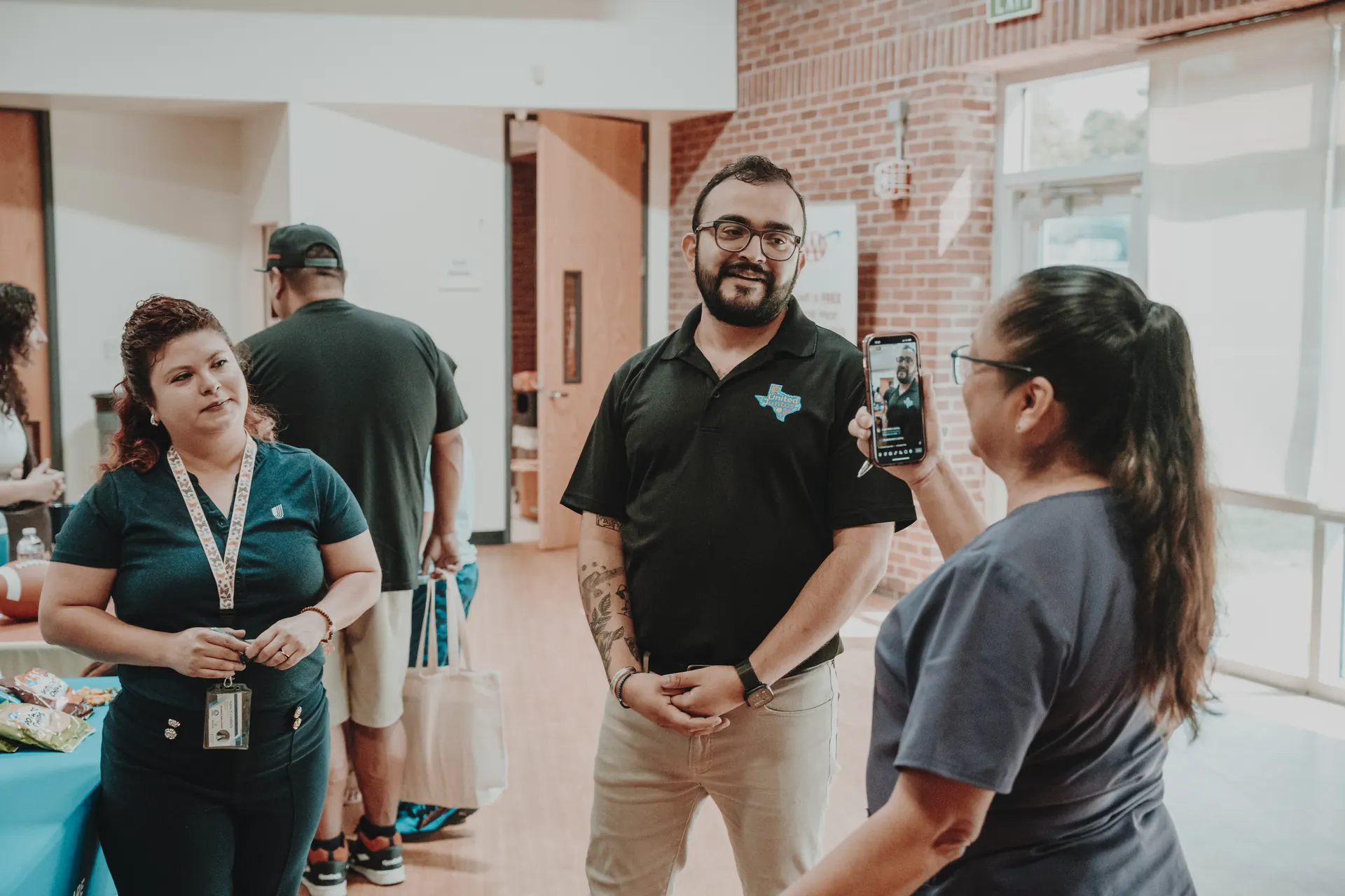 A United Juntos co-founder in a team polo talking with neighbors at an event